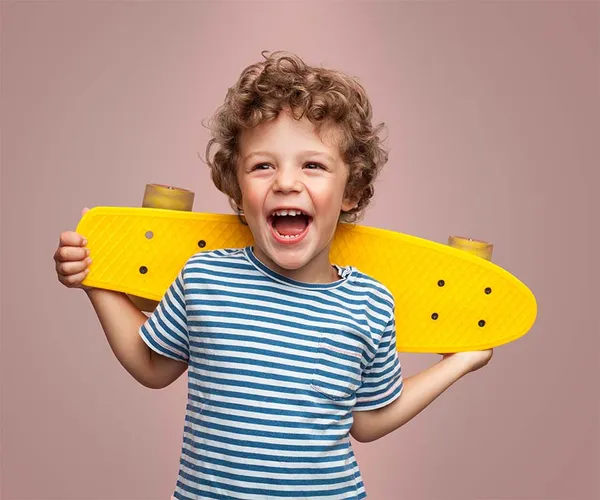 Happy child holding a skateboard and smiling